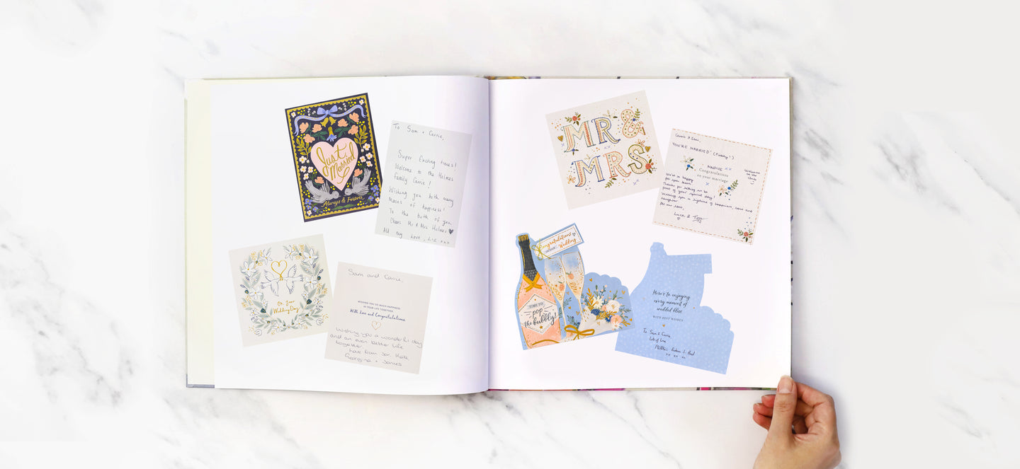 An open book with photos of old wedding cards printed on the pages, showing the fronts of the cards and inside messages from wedding guests