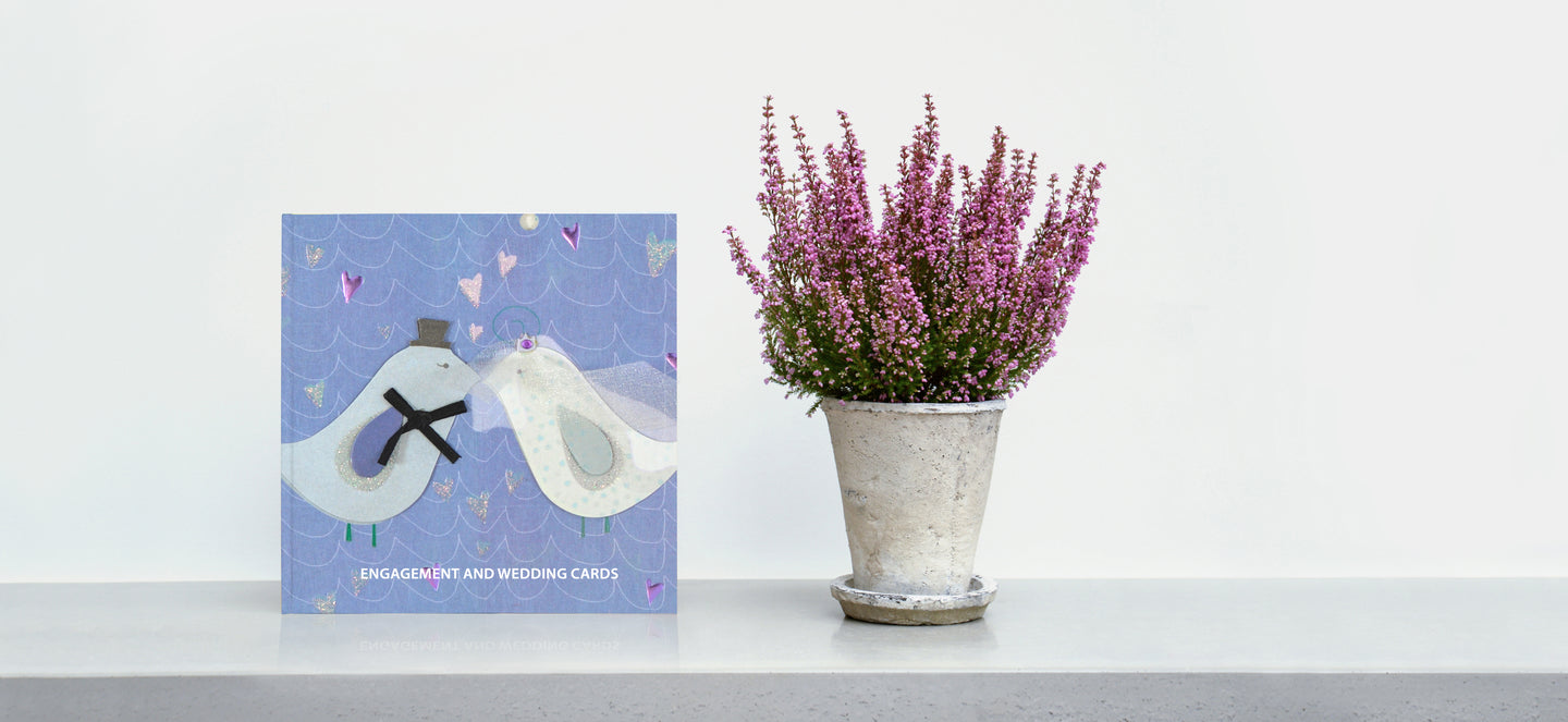 Wedding card keepsake book standing up on a shelf next to a plant