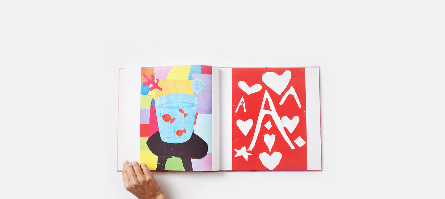 Hand turning page of book with brightly coloured kids' paintings in it