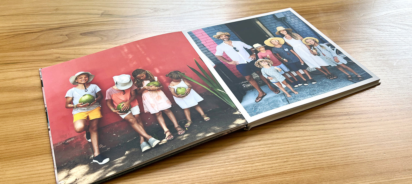 An open layflat photo book showing two colourful photos of a family on holiday somewhere warm