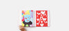 Hand turning page of book with brightly coloured kids' paintings in it