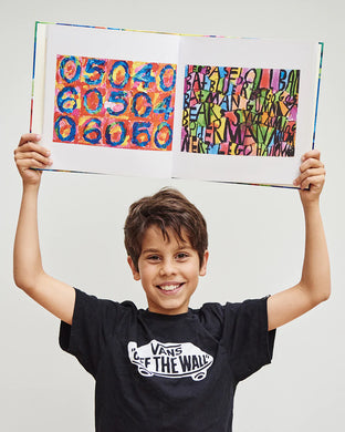 A child holding open a custom art keepsake book with colorful abstract patterns.