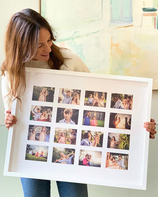 A woman holding a framed photo collage with multiple family photographs arranged in a grid pattern.