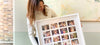 A woman holding a framed photo collage with multiple family photographs arranged in a grid pattern.